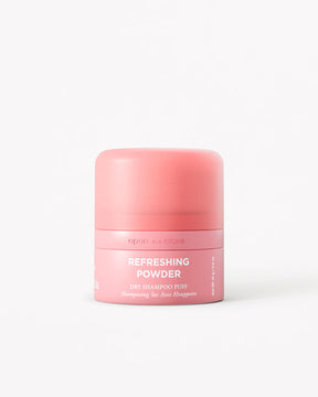 A pink cylindrical jar of Refreshing Powder Dry Shampoo on a clean white background.